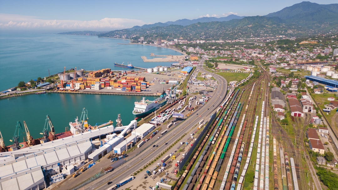 Busy port with ships, containers, and train tracks.